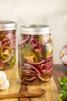 two mason jars filled with pickled onions and peppers on top of a wooden table