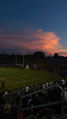 the sun is setting over a soccer field as people sit in bleachers and watch