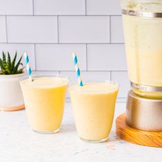 two glasses filled with smoothie next to a blender