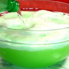 a green drink being poured into a glass bowl