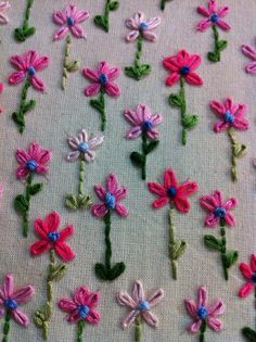 some pink and blue flowers are on a white table cloth with green stems in the middle