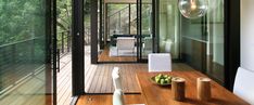 a wooden table sitting on top of a wooden floor next to a glass wall with sliding doors