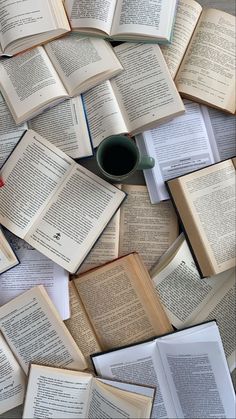 many open books are scattered around a coffee mug