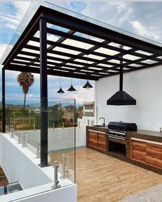 an outdoor kitchen and grill area with wood flooring