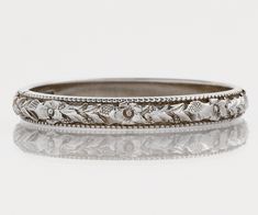 an antique wedding band with flowers and leaves on it's sides, set in white gold