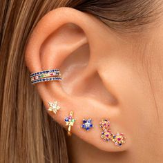 a close up of a person wearing ear piercings with different colored stones on them