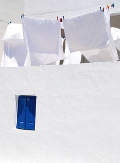 there is a white building with blue doors and clothes hanging on the line above it