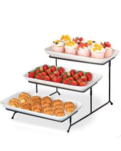 two serving trays filled with pastries and strawberries on top of each other