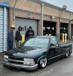 a black truck parked in front of a building with two men standing next to it