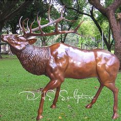 a bronze statue of a deer with antlers on it's back in the grass