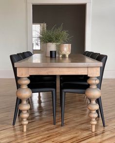 a dining table with black chairs and a potted plant on top of the table