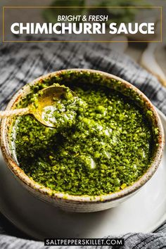 a white bowl filled with pesto sauce on top of a gray cloth and wooden spoon