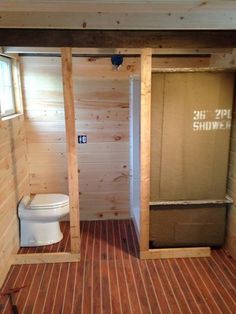 the inside of a small bathroom with wood walls and flooring, including a toilet