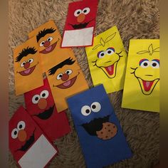 several sesame street characters are on the floor with some paper bags in front of them