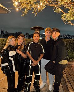 a group of people standing next to each other on a wooden floor near a tree