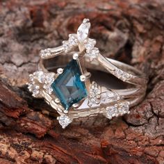 a blue diamond ring sitting on top of a piece of wood with diamonds around it