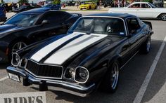 two black and white muscle cars parked next to each other