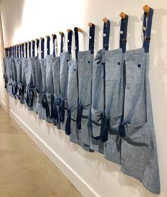 blue aprons hanging on the wall with wooden handles