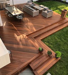 a wooden deck with chairs and an umbrella on it in the middle of a yard