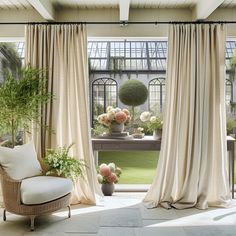 a living room filled with lots of windows covered in drapes and flowers on top of them