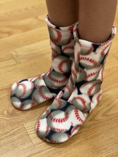 the legs and feet of a person wearing socks with baseballs on them, standing on a wooden floor