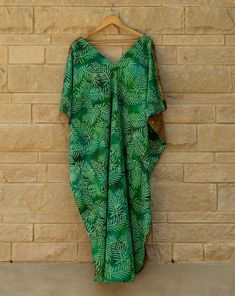 This breathable cotton kaftan combines regal drape with down to earth prints. The rich green and deep yellow and brown palm prints are sure to turn heads at brunch or an outdoor party. The side slits add movement and show off your legs, while the bra savers hold everything in place. All kaftans are handmade in small batches in Austin,TX. Sizes and color may slightly vary due to lighting and screen settings. Green Batik Print Kaftan For Summer, Green Printed Kaftan With Kimono Sleeves, Green Summer Kaftan With Batik Print, Green Dresses With Side Slits For Vacation, Green Batik Print Dress For The Beach, Tropical Green Kaftan For The Beach, Green Vacation Dress With Side Slits, Green Bohemian Kaftan With Relaxed Fit, Green Tunic Kaftan For Beach Season