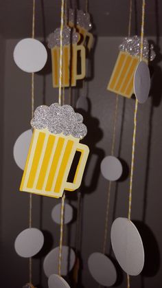 paper beer mugs hanging from strings in the shape of stars and circles on a dark background