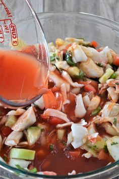 someone pouring sauce into a glass bowl filled with food