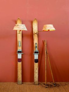 two skis are standing next to each other in front of a red wall and lamp