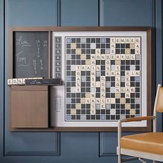 a framed scrabble board and chair in front of a chalkboard with words written on it