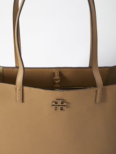 McGraw tote bag in brown grained leather with embossed Double T logo on the front. It features fixed double handles, interior hook closure, one main interior compartment and one interior zip pocket. Dimensions: 11.4x14x5.5 inches Size nationality: UNI Product number: 3852034 Product code: 152221227 Composition: 100% leather Army Post, T Logo, Designer Totes, Leather Shops, Tote Bag Design, Tory Burch, Zip Pockets, Handles, Composition