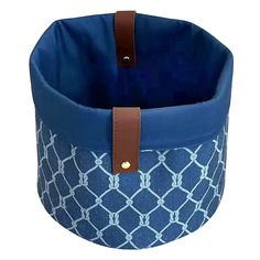 a blue and white patterned basket with brown leather handles on the bottom, sitting in front of a white background