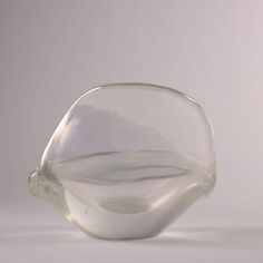 a clear glass vase sitting on top of a white tablecloth covered floor next to a gray wall