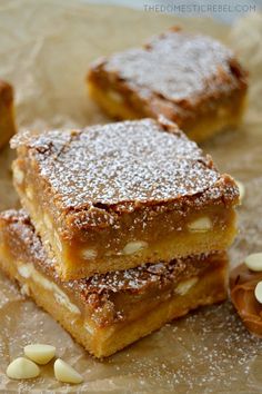 three pieces of dessert sitting on top of a piece of wax paper next to nuts