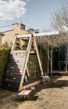 a child's wooden swing set with climbing bars and toys in the back yard