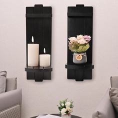 two wall mounted candle holders with flowers and candles on them in front of a couch