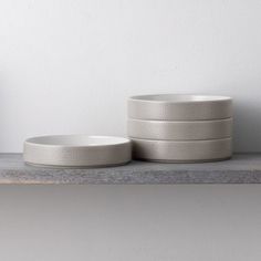 three white bowls sitting on top of a shelf