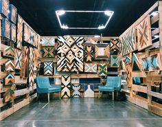 a room with several pieces of wood on the wall and two blue chairs in front of them