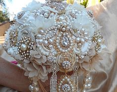 the bridal bouquet is adorned with pearls and brooches