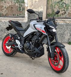 a silver and red motorcycle parked in front of a building with graffiti on the walls