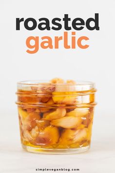 a glass jar filled with roasted garlic on top of a white table next to an orange and black sign