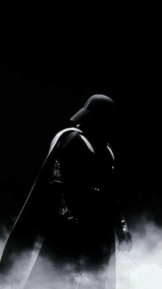 a black and white photo of a man dressed as darth vader in the dark