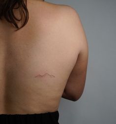 the back of a woman's breast with a small tattoo on her left side