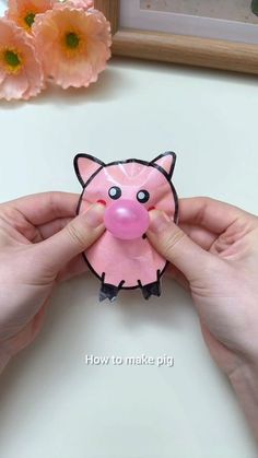 a person holding a pink pig toy in their hands