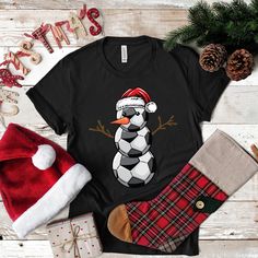 Kick off your Christmas celebrations with our Soccer Santa Snowman design. A perfect blend of the world's most popular sport with festive holiday cheer. Suitable for soccer fans and players of all ages, this attire adds a sporty touch to your holiday gatherings. * Please do not hesitate to contact the shop with any questions.  * Not all available colors can be listed in the color dropdown. The size charts include all color variations per style. If you want a color not in the dropdown just select black & type in the color in the order comments. We will refund if we don't have the color in stock. * Want the design printed on the back? Just add this request to the order comments box at checkout! * If you need to cancel an order please reach out as soon as possible. Orders can only be cancelle Black T-shirt For Winter Sports Events, Winter Sports Crew Neck T-shirt, Winter Sports Event Crew Neck T-shirt, Pre-shrunk T-shirt As Winter Gift, Police Shirts, Snowman Design, Long Sleeve Tank Top, Popular Sports, Soccer Fans