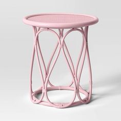 a pink side table with wicker design on the top and bottom, against a white background