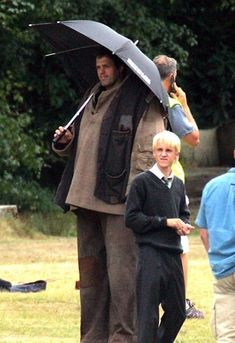 a group of people standing around each other with umbrellas in their hands and one man holding an umbrella over his head