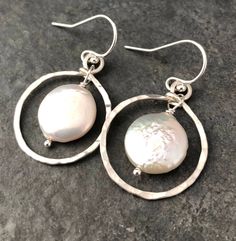 There is a reason why classic style is classic style, and you just can't go wrong with pearls. These earrings feature gorgeous 11mm coin pearls framed by hammered sterling silver circles, and finished with a simple ear wire. These pearls are a contemporary shape, and have a wonderful white to cream color and a great luster. Please note that while I select the best pearls available, freshwater pearls are a natural material and often have some minor imperfections. All items are packaged in a gift Pearl Bridal Earrings In Silver, Sterling Silver Bridal Earrings With Pearl Drop, Elegant Small Hoop Birthstone Jewelry, Silver Pearl Bridal Earrings, Silver Dangle Pearl Earrings For Anniversary, Anniversary Jewelry With Matching Earrings, Silver Earrings With Pearl Charm As Gift, Classic Pearl Charm Hoop Earrings For Anniversary, Sterling Silver Hoop Earrings With Pearl Drop For Anniversary