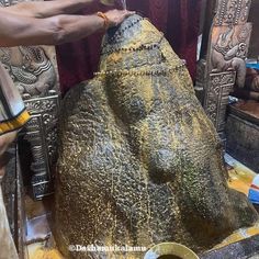 a man is carving an elephant statue with gold paint