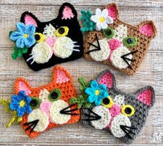 three crocheted cats with flowers on their heads are sitting next to each other